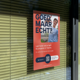 "Good, but is it real?" campaign poster in a window