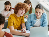 Two Students Work Together on Laptop